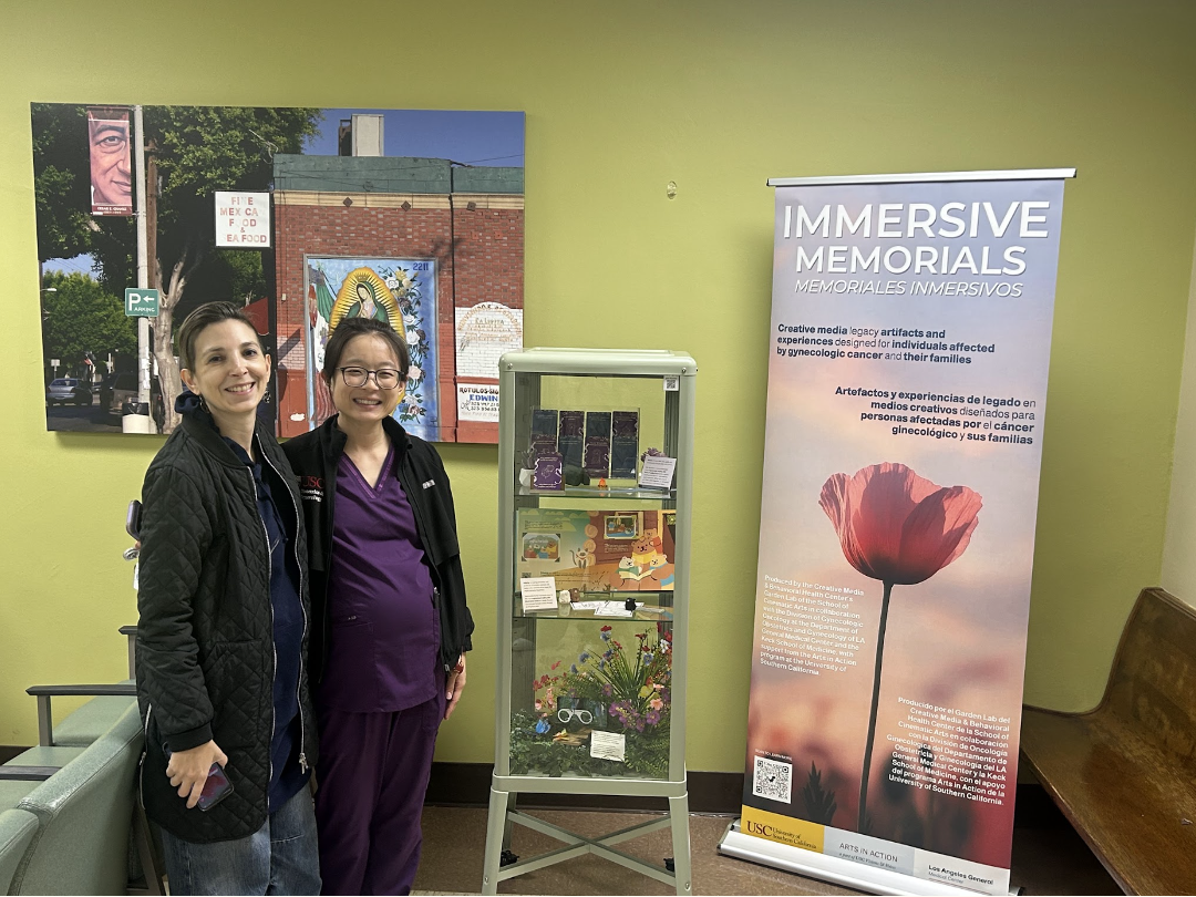 Two people in front of a glass cabinet of art objects and roll-up gallery banner